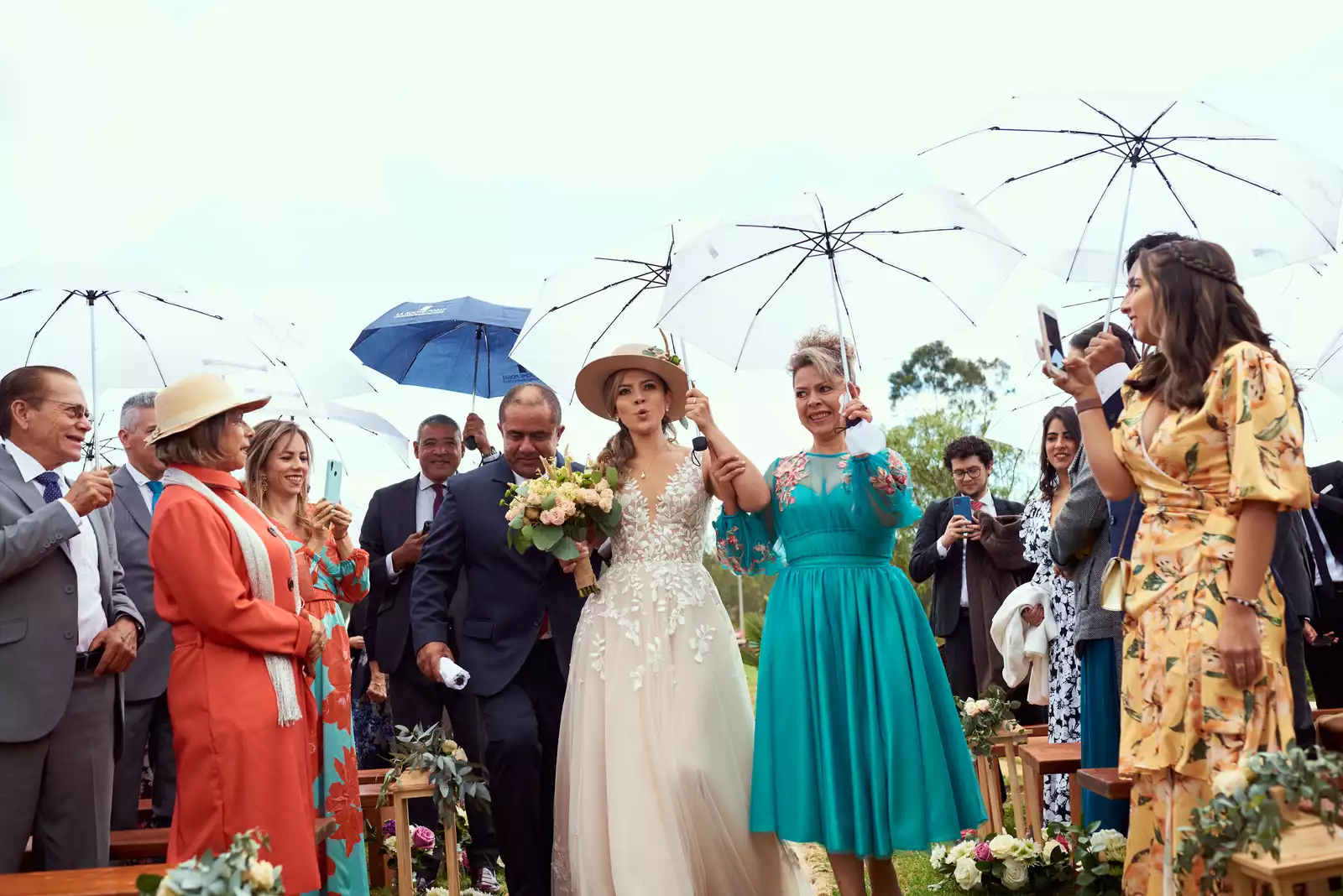 Liz llegando a su ceremonia bajo un paraguas blanco en Ave María